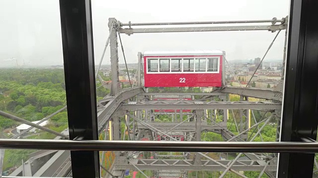 从摩天轮的窗口看过去。看多云的天空，树木和建筑物，维也纳，奥地利视频素材