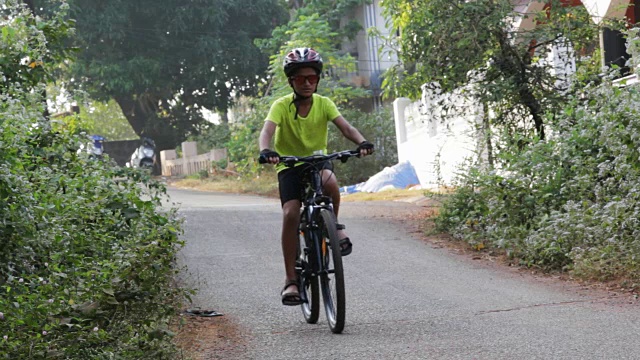 在印度果阿附近的公路上骑自行车的小男孩视频素材