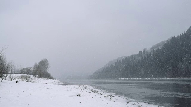 冬季公园里的河。冬天的风景。雪堆在河岸上。冬河有雾。河岸上覆盖着雪。有雾的冬天。下雪的冬天的公园。被雪覆盖的树。寒冷的天气视频素材