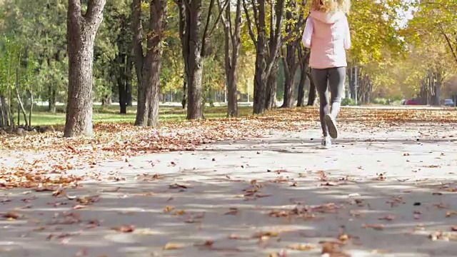 女人跑公园年轻活跃的健身女跑步者锻炼户外运动女孩慢跑秋天黄叶树视频下载