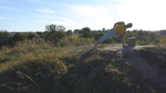 有人在户外练习瑜伽动作和姿势。年轻人站在自然的瑜伽姿势。运动员在山上做力量训练。美丽的天空与太阳的背景。健康积极的生活方式。视频素材