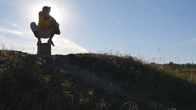 剪影的运动男子坐在户外瑜伽姿势。瑜伽修行者练习瑜伽动作和自然位置。运动员正在热身。美丽的天空和太阳作为背景。健康积极的生活方式视频素材