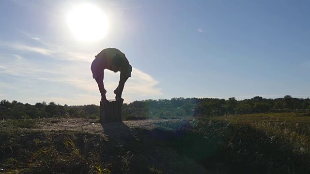 运动员在山上做倒立。年轻人站在自然的瑜伽姿势。有人在户外练习瑜伽动作和姿势。美丽的天空与太阳的背景。健康积极的生活方式。近距离视频素材