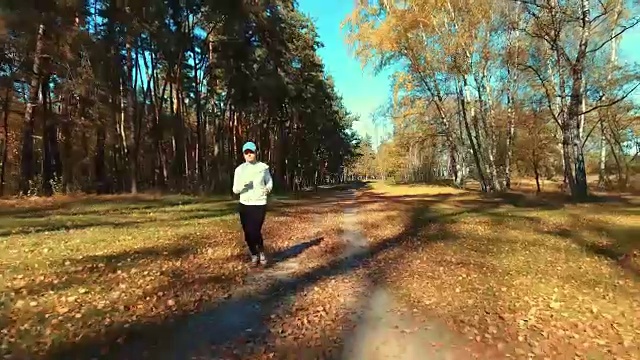 女孩在清晨的森林里奔跑。体育运动视频下载