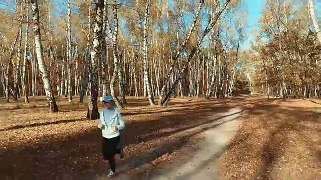 女孩在清晨的森林里奔跑。体育运动视频素材