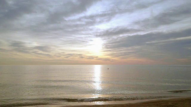 日出海滩。海上日出的田园诗般的景色。海浪慢慢地溅起沙子视频素材