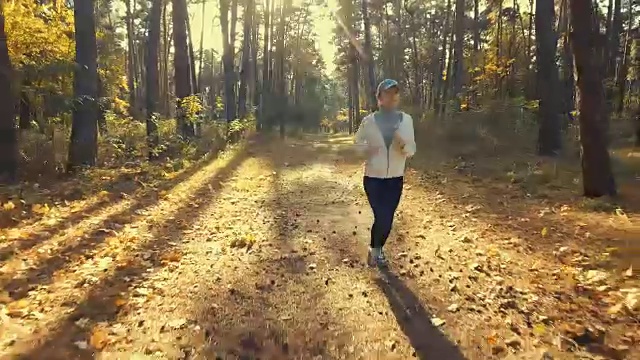 女孩在阳光明媚的清晨森林里奔跑。体育运动视频素材