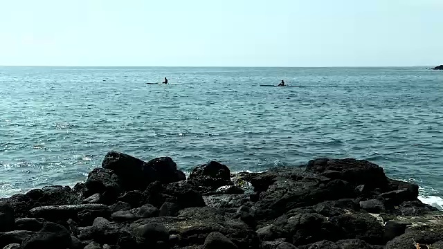 海洋天空和黑色的熔岩岩海岸与独木舟的背景视频素材