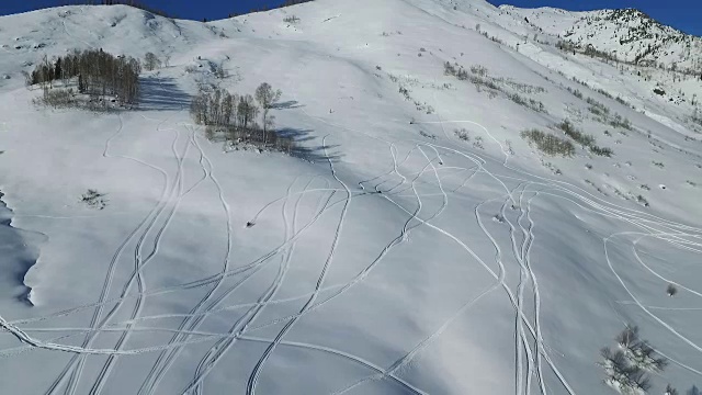 雪上摩托在粉状雪中冲下一座山视频素材