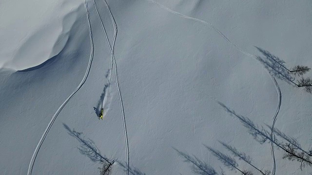 雪上摩托在粉状雪中冲下一座山视频素材