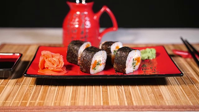 以竹子为背景，用筷子夹在红色盘子里的日本寿司视频素材