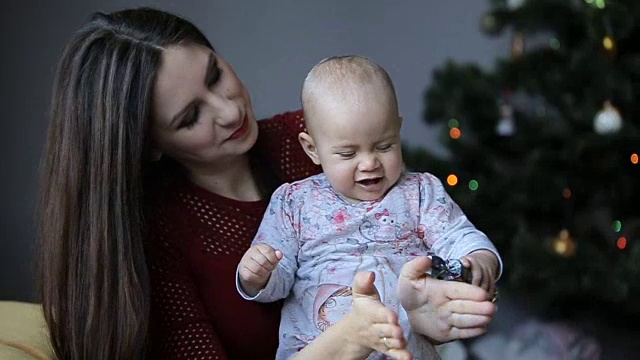 年轻迷人的妈妈和她可爱的女儿在家里玩圣诞树视频素材