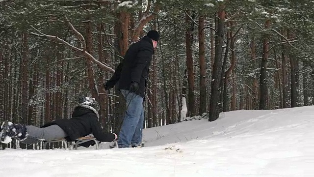 父亲正拉着他女儿的雪橇。96帧/秒视频素材