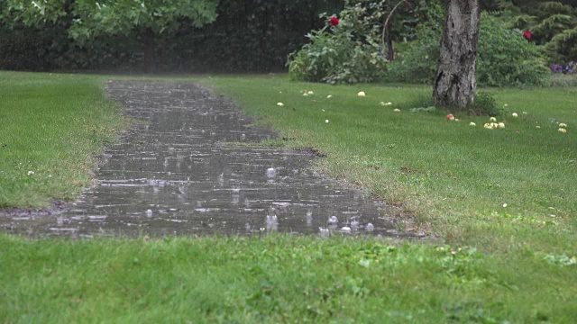 大雨水滴落在花园的石头路面上，在雨天溅起水花。FullHD视频素材