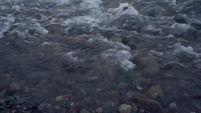 浅水河与灰色的卵石在河床上运行的岩石近距离镜头视频素材