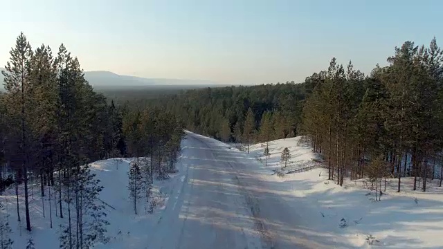 航拍相机上升在冬季道路从近距离的整个景观到地平线。北雪森林视频素材