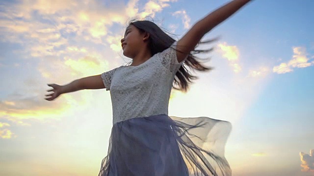 晚霞中女子向天空张开双臂的剪影，慢镜头视频下载