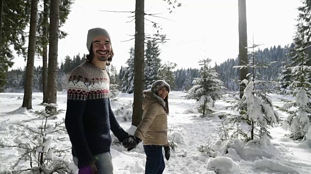 一对冬雪森林行走的男人和女人手牵手在雪山公园视频素材