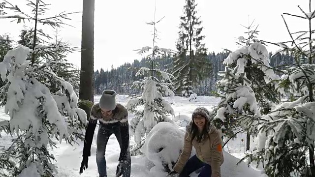 一对冬季森林行走的男人和女人扔雪在下雪的公园里玩视频素材