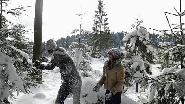 一对冬季森林行走的男人和女人扔雪在下雪的公园里玩视频素材