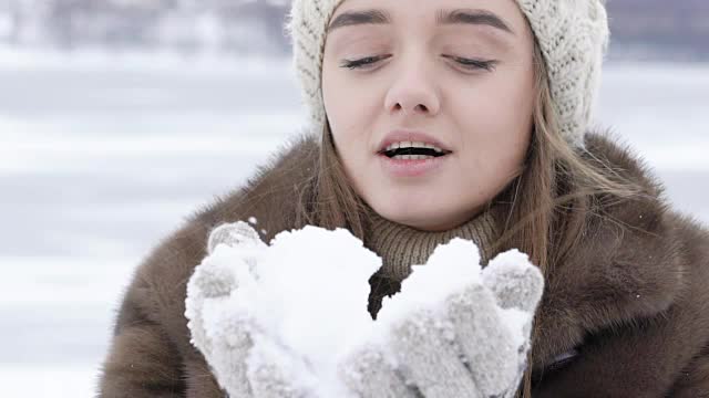 美丽快乐的女孩在户外吹雪。慢慢地视频素材