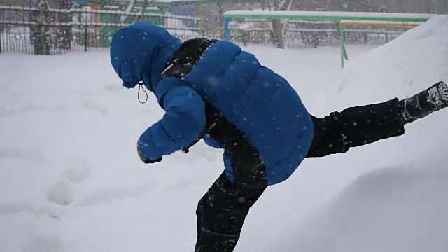 一个孩子跳进冬季公园的雪地里。暴风雪视频素材