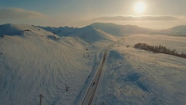 黄昏时分，几辆汽车在山旁结冰的路上行驶。视频素材