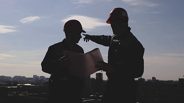 两个建筑工站在建筑工地的剪影视频下载