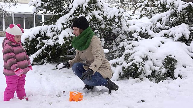 快乐的女人带着女儿玩着初冬的雪。雪花落视频素材