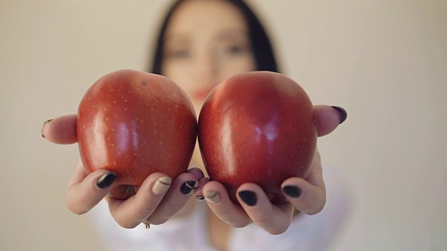 女孩的手拿着两个大红苹果在镜头前，模糊的背景全高清视频素材