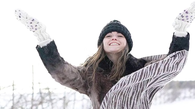 那个女孩在冬日里对着镜头扬起雪花微笑。慢慢地视频素材