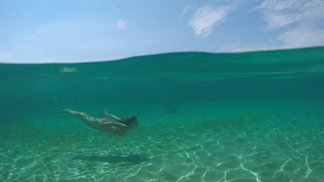 水下:快乐的年轻女子在水下游泳，到水面呼吸空气视频素材