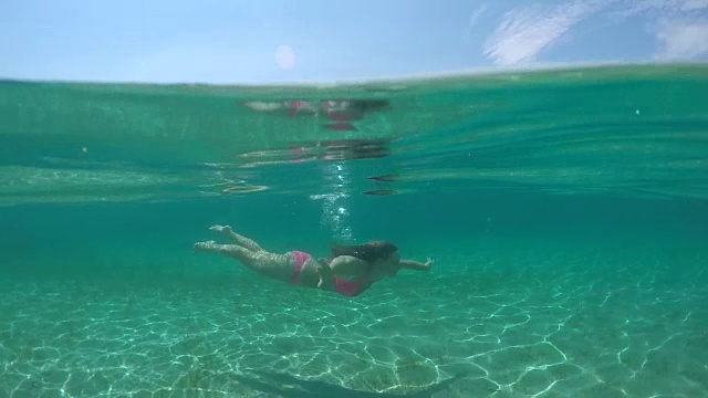 水下:迷人的女孩在水下游泳，到水面呼吸空气视频素材