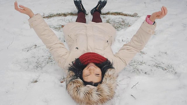 美丽快乐的青少年模特女孩有乐趣在冬季公园。美丽的女孩在户外吹雪纺纱。享受大自然。视频素材