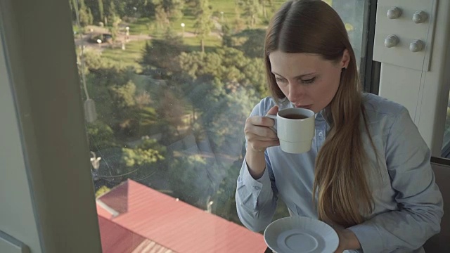 女孩在时尚餐厅的窗口喝茶视频素材