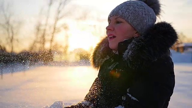 女孩用手在夕阳的背景上吹雪视频素材