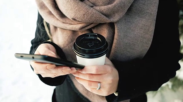 年轻女性带着手机，热水瓶在冬天的户外视频素材