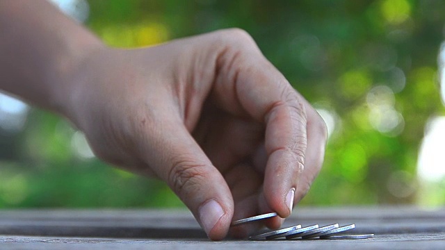 做空钱币的女人手过自然绿叶浅景深视频素材