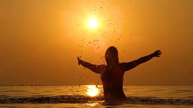 慢镜头:可爱的女人站在浅海中，溅起水花视频素材