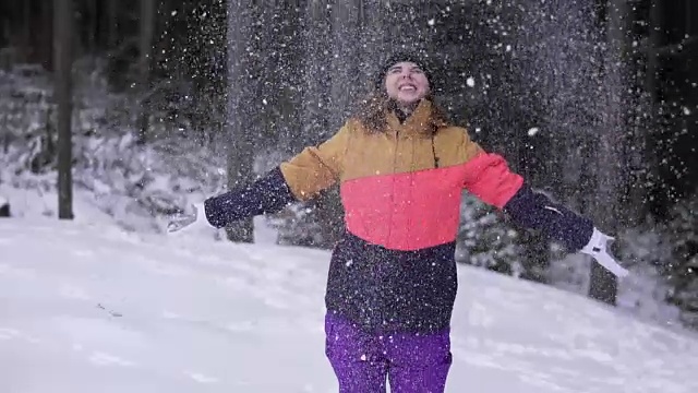 冬天的风景美丽的雪花快乐的女人玩着飘落的雪花。年轻的女孩玩扔雪玩在外面与手臂在空中嬉戏的冬天。视频素材