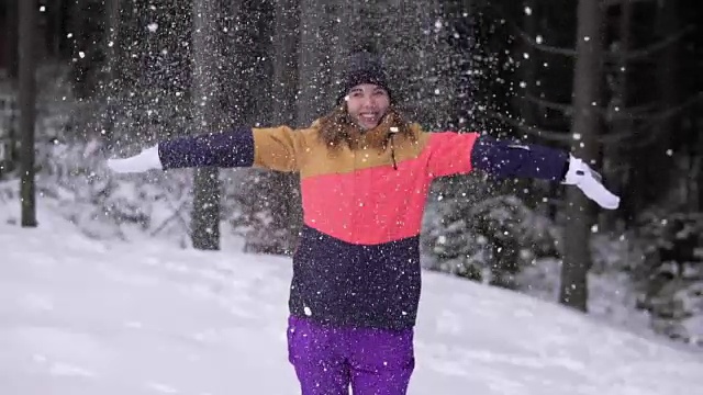 冬天的风景美丽的雪花快乐的女人玩着飘落的雪花。年轻的女孩玩扔雪玩在外面与手臂在空中嬉戏的冬天。视频素材