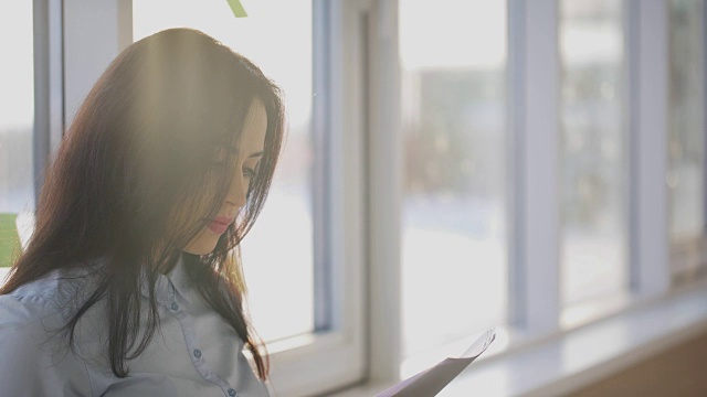 年轻美丽的女人检查不同的文件靠近窗口视频素材