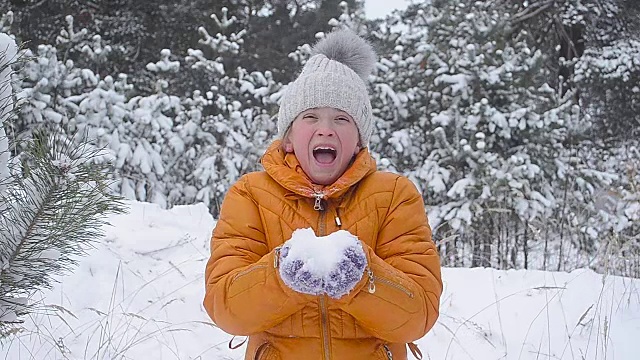 十几岁的女孩用手吹雪，快乐的女孩笑着在冬季公园享受家庭假期。视频素材