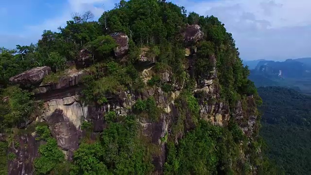 空中拍摄:一名男子在山上的一个岩石观景台上操控无人机。视频素材