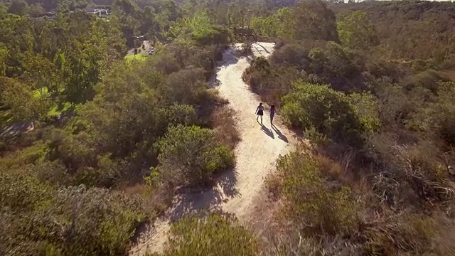 母亲和女儿在空旷的小路上徒步旅行，航拍视频素材