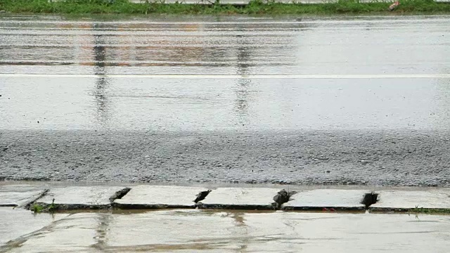 雨点溅落在柏油路上。视频素材