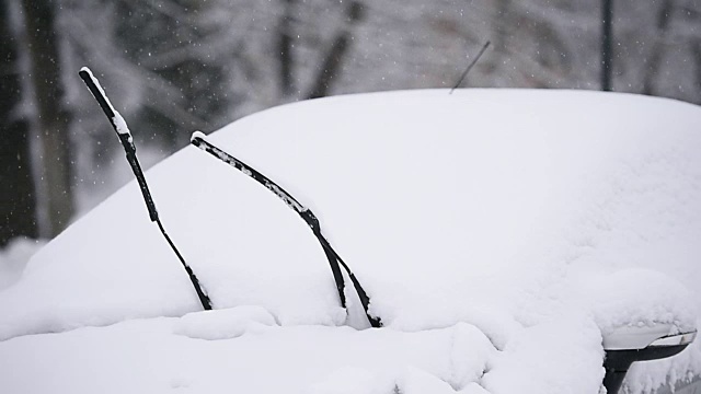 一辆被雪覆盖的汽车的挡风玻璃刮水器视频素材