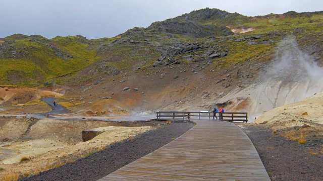 在冰岛的地热区Seltun的木制跑道上，在雨天，游客们正在行走视频素材