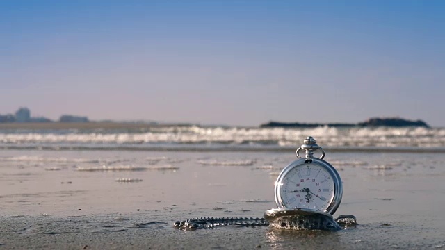 在潮湿的沙滩和日落的海浪上的袖珍钟视频素材