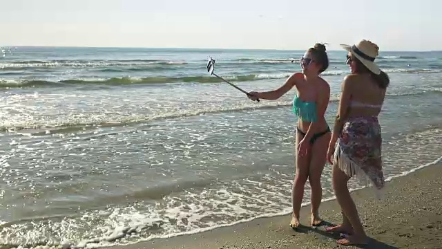 两名年轻女性在海滩上进行视频通话视频素材